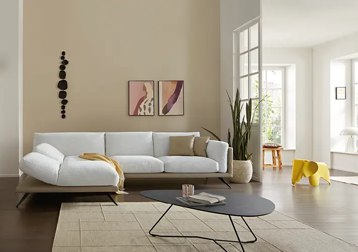 Weißes Sofa mit Couchtisch, Pflanze, Sessel und gelbem Beistelltisch